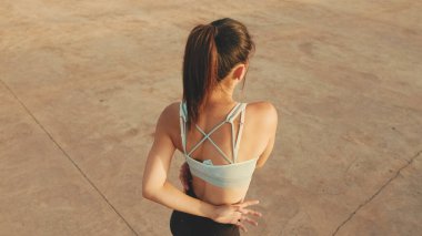 Asian girl in sports top does workout, stretching and gymnastics at morning time. View from above