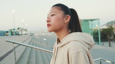 Asian girl wears sportswear, climbs stairs, looks up at morning time