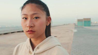Close up of asian girl wearing sportswear looking at camera at morning time
