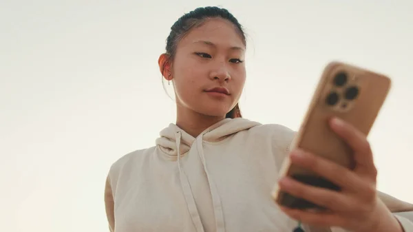 Close Asian Girl Sportswear Uses Phone While Standing Embankment Morning — Stockfoto