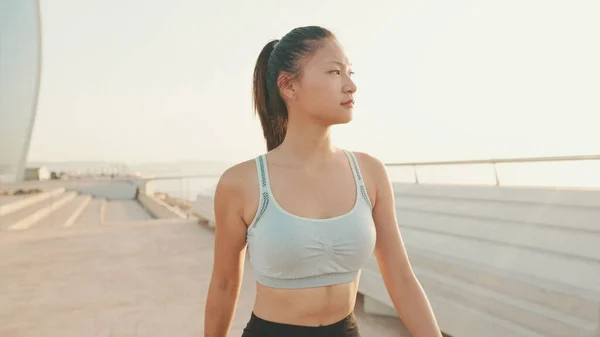 Asian girl in sports top walking outside at morning time
