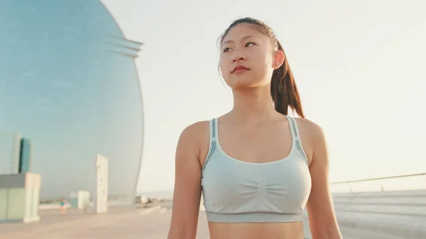 Asian girl in sports top walking outside at morning time