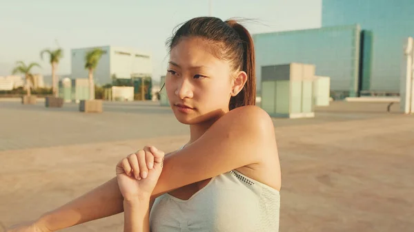 Asian girl in sports top does workout, stretching and gymnastics at morning time.