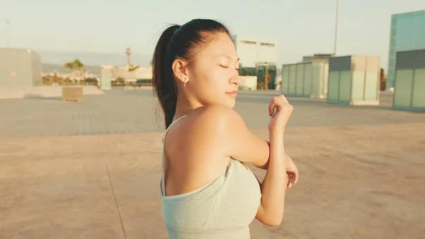 Asian girl in sports top does workout, stretching and gymnastics at morning time.