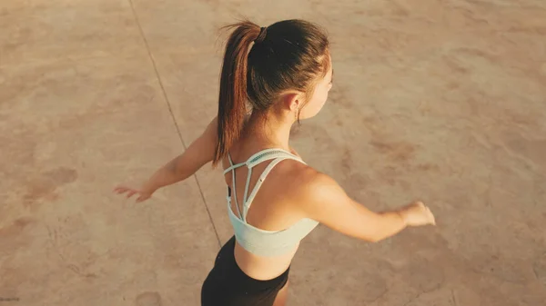 Asian girl in sports top does workout, stretching and gymnastics at morning time. View from above