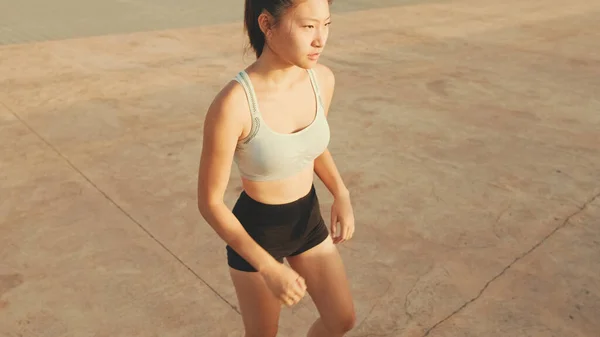 Asian girl in sports top does workout, stretching and gymnastics at morning time. View from above