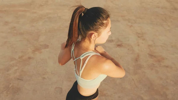 Asian girl in sports top does workout, stretching and gymnastics at morning time. View from above