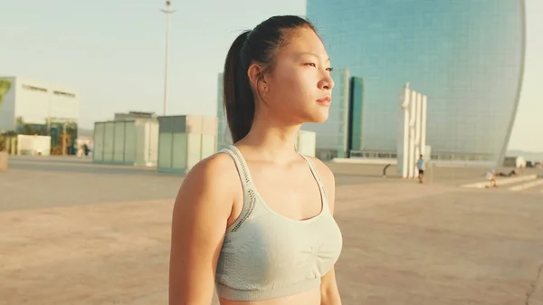Asian girl in sports top walking outside at morning time