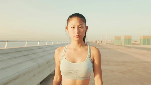 Close up, asian girl in sports top looks at the camera