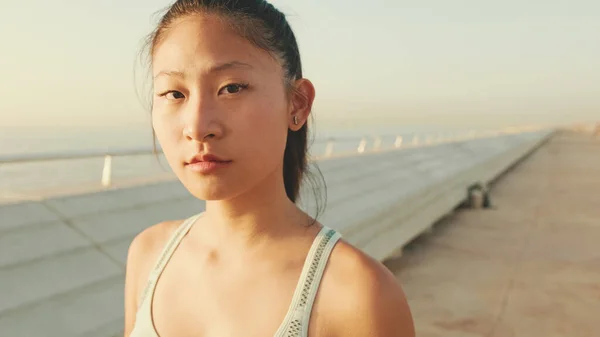 Close up, asian girl in sports top looks at the camera