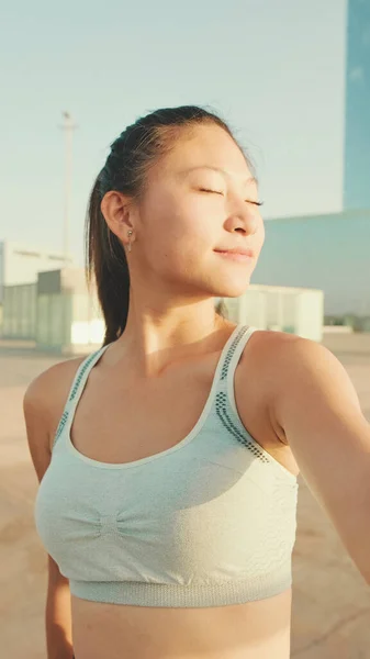 Smiling asian girl in sports top makes selfie while standing on the embankment in the morning light