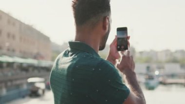 Genç adam limandaki akıllı telefon yatlarında fotoğraf çekiyor. Arka plan