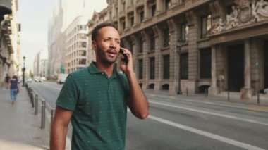 Yolun kenarında dikilen genç adam cep telefonuyla konuşuyor.