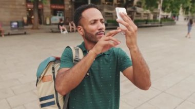 Genç turist, eski şehrin meydanında dururken cep telefonuyla fotoğraf çekiyor.