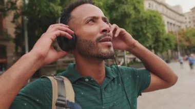 Yakından, genç turist eski şehrin meydanında yürüyor, kulaklıkla müzik dinliyor, ellerini kulaklıklara koyuyor.