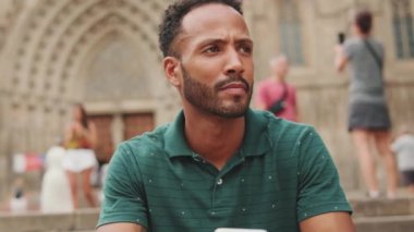 Genç adam Barcelona 'da Sagrada Familia' nın merdivenlerinde oturur ve etrafına bakar.