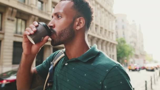 Молодой Человек Идет Улице Оглядывается Пьет Кофе — стоковое видео