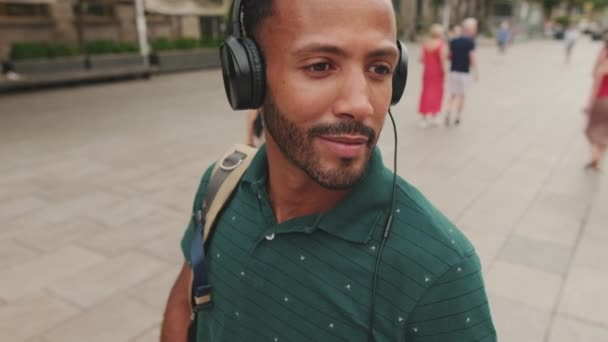 走近点 年轻人游客在古城的广场上散步 用耳机听音乐 — 图库视频影像
