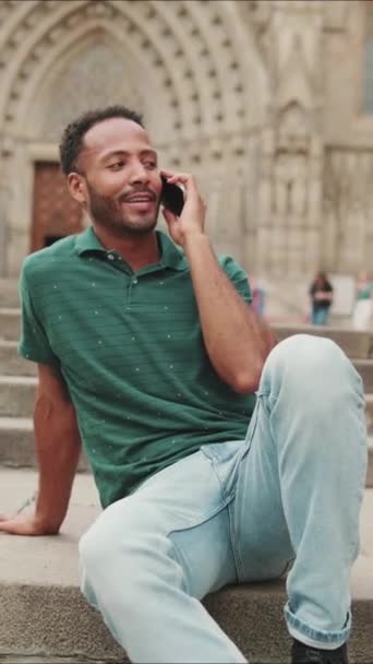 Vertical Video Happy Young Man Sits Steps Barcelona Talking Smartphone — Stock Video