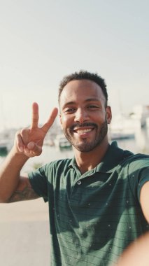 Limanda arka planda yatlarla otururken telefondan video görüşmesi yapan mutlu genç adam.