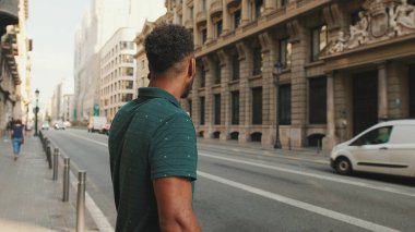 Yolun kenarında dikilen genç adam cep telefonuyla konuşuyor.