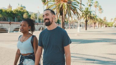 Interracial couple walks down the street holding hands