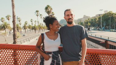 Close-up of happy interracial couple talking while standing on bridge
