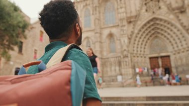 Omzunda sırt çantasıyla, eski şehrin meydanında dikilirken manzaraya bakan genç turistin yakın çekimi. Arka plan