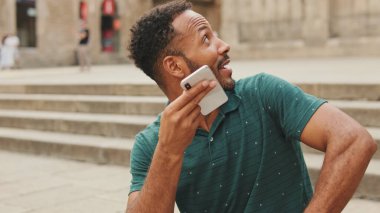 Yaklaş, mutlu genç adam Barcelona 'da Sagrada Familia' nın merdivenlerinde oturuyor, cep telefonundan sesli mesaj gönderiyor.