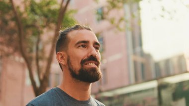 Young smiling man with beard walking and looking around at the old city background