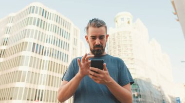 Young man with beard uses map application on mobile phone