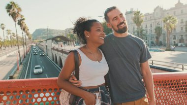 Close-up of happy interracial couple talking while standing on bridge