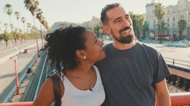 Close-up of happy interracial couple talking while standing on bridge
