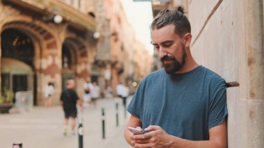 Young man with beard uses an application on smartphone
