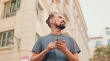 Young man with beard uses map application on mobile phone