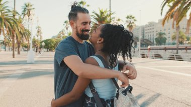 Happy interracial family hugging and kissing outside