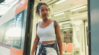 Young mixed race woman getting off the train at the railway station