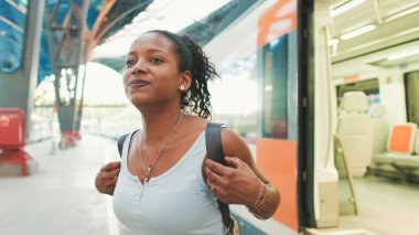 Young mixed race woman getting off the train at the railway station