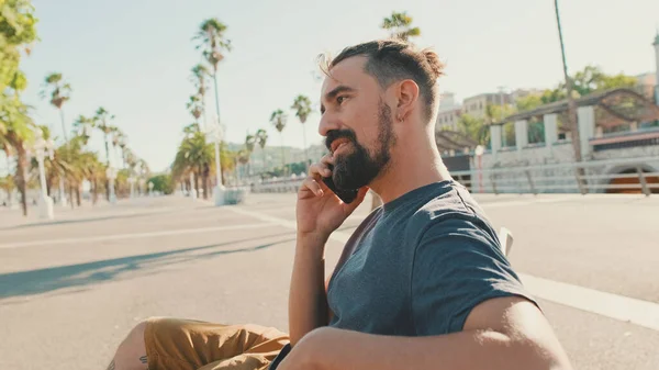 Young Smiling Man Beard Sits Bench Uses Cellphone — Stockfoto