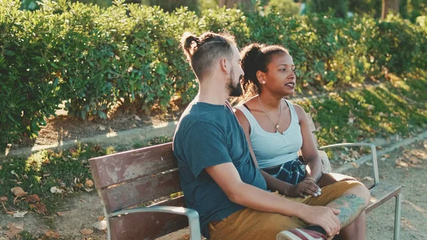 Interracial Couple Talking While Sitting Bench Backlight — стокове фото