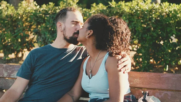 Happy Smiling Interracial Couple Kissing While Sitting Bench — Stock fotografie