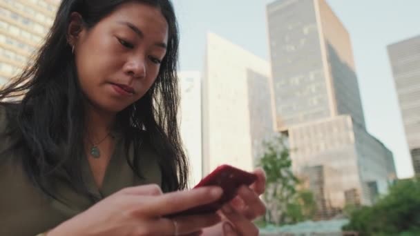 Zbliżenie Młoda Dziewczyna Używa Smartfona Siedząc Nowoczesnym Tle Budynków — Wideo stockowe