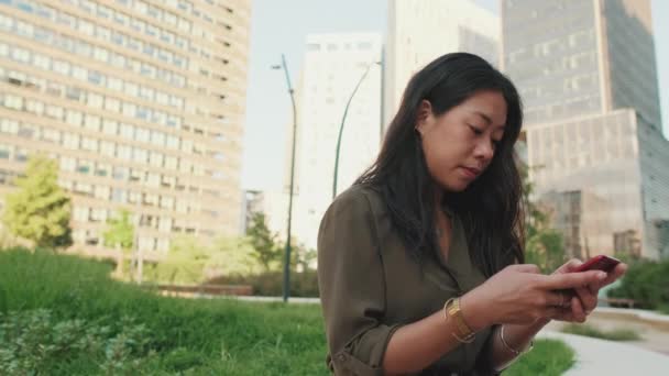 Jovem Usa Smartphone Enquanto Senta Prédios Modernos Fundo — Vídeo de Stock