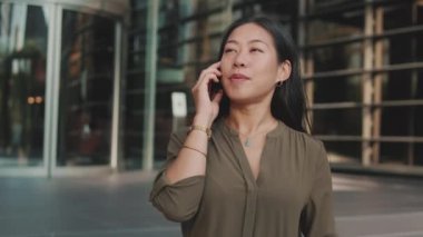 İş merkezinde çalışan genç bir iş kadını akıllı telefondan konuşuyor.