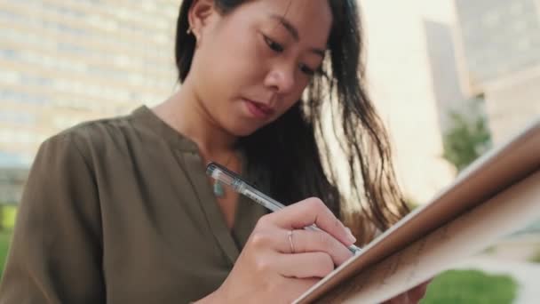 Close Young Girl Makes Notes Notebook While Sitting Modern Buildings — Stock Video