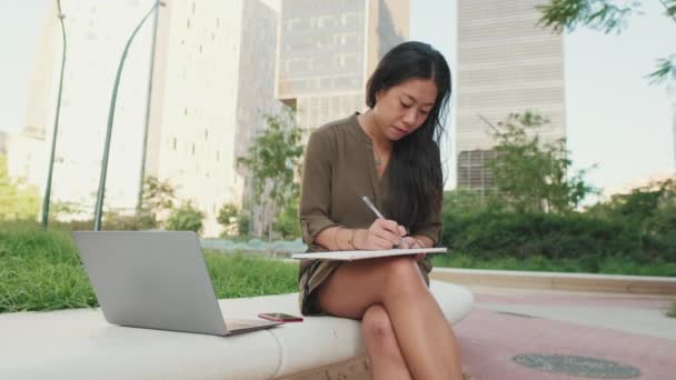 Jovem Usa Laptop Faz Anotações Notebook Fora Prédios Modernos Fundo — Vídeo de Stock