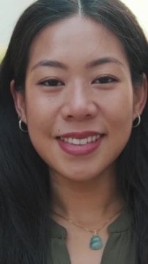 Kameraya bakıp gülümseyen genç bir kızın yakın çekim görüntüsü.