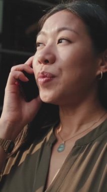 Kapatın, genç iş kadını iş merkezinin arka planında akıllı telefondan konuşuyor.