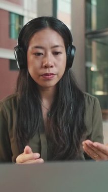 Kulaklıklı genç bir kadın dizüstü bilgisayarında video konferansı düzenliyor.