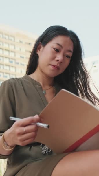 Video Vertical Jovencita Toma Notas Cuaderno Mientras Sienta Los Edificios — Vídeos de Stock